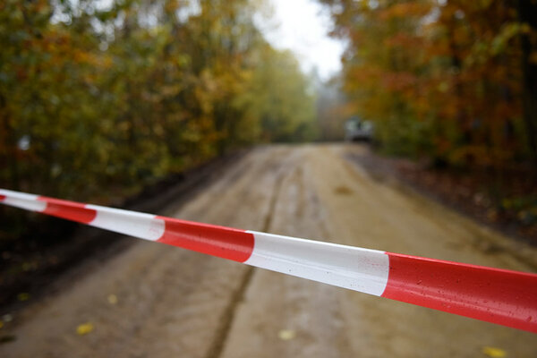 Absperrband über einen Waldweg gespannt. 