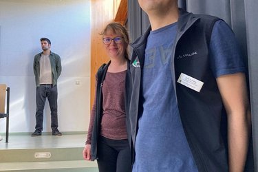 Eine Studiengangkoordinatorin und ein Studiengangkoordinator lächeln in die Kamera.