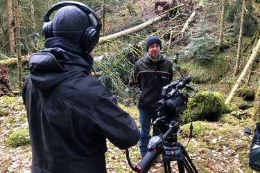 Kameramann filmt Referenten im Wald