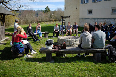 Studierende sitzen an der Grillstelle im Arboretum der Hochschule Rottenburg und hören der Referentin zu