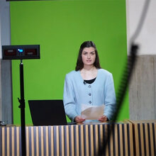 Studierende vor einem Greenscreen in der Aula der Hochschule Rottenburg. Im Vordergrund stehen Leuchten und Kameras.