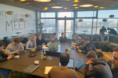 Studierende arbeiten in Gruppen in einem großen Konferenzraum