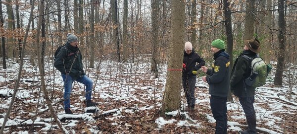 Studierende und Referenten stehen um einen Baum und diskutieren