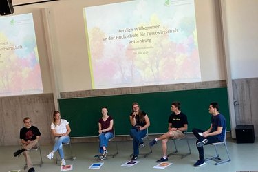 6 Studierende sitzen auf der Bühne und stellen ihren Stdueingang vor