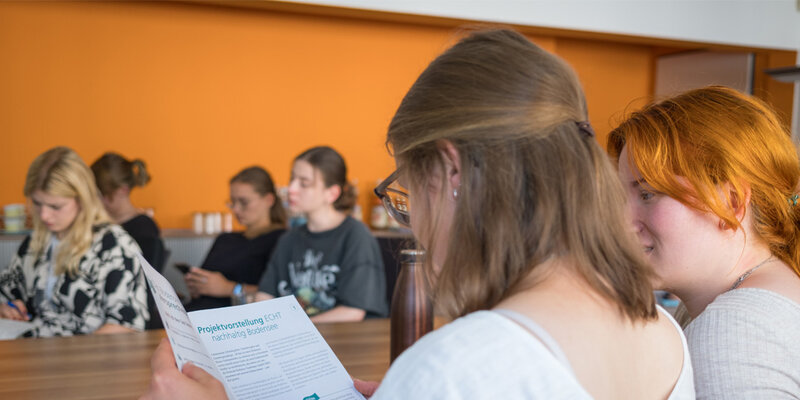 Zwei Studentinnen schauen sich eine Broschüre an