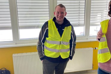 Student mit gelber Warnweste lächelt in die Kamera