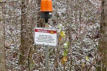 Hinweisschild mir rotem Blinklicht: Bei Eisanhang Durchgang verboten – Wanderer müssen auf eine Umleitung ausweichen, wenn das rote Licht blinkt.