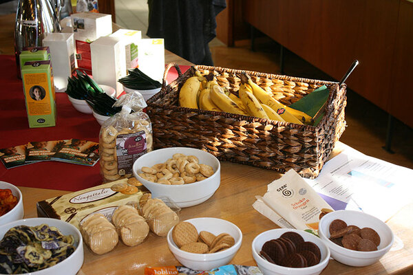 Auf einem Buffet-Tisch stehen Fairtrade-Produkte: Bananen und verschiedene Sorten Kekse.