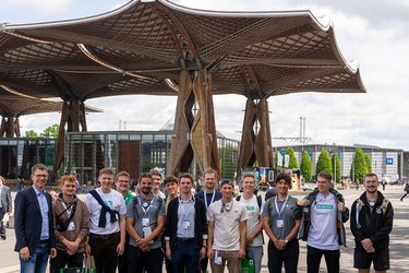 Gruppenfoto mit Studierenden vor einem Holzdach