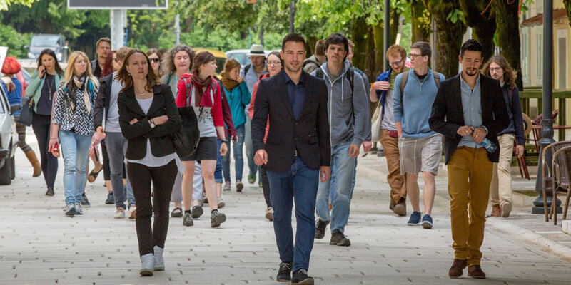 Studierende und ihre Professorin laufen gemeinsam bei einer Lehrfahrt durch eine Fußgängerzone