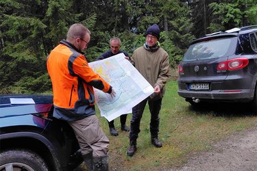 Ein refernet auf einem Waldweg erläuert den Studiernden ein Waldkarte