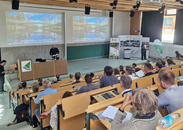 Blick über die Besucher zu der Bühne mit Referent