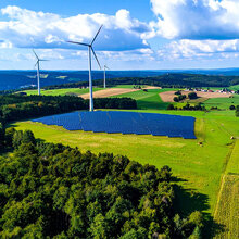 Blick in eine grüne Landschaft mit Windrädern und Solaranlagen