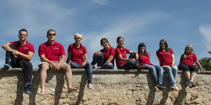 Gruppenbild: Studierende des Studiengangs Erneuerbare Energien sitzen zusammen auf der Mauer auf der Nordseite des Schadenweilerhofs - Hauptgebäude der Hochschule Rottenburg