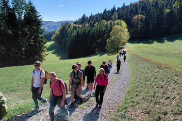 Studierende wandern über eine Wiese