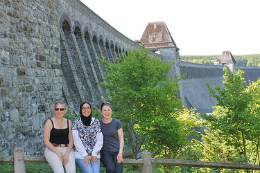 Gruppenfoto mit drei Studentinnen vor Staumauer