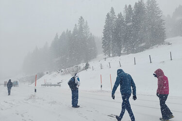 Studierende laufen bei Schneefall durch die Winterlandschaft im Allgäu