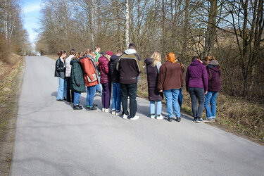 Studierende stehen als Gruppe auf einer schmalen Straße