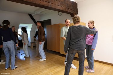 Mehrere Studierende stehen in einem Hörsaal in Kleingruppen