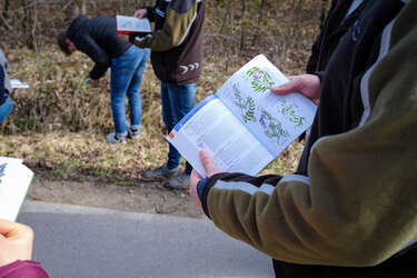 Eine Studentin hält ein Bestimmungsbuch in die Kamera