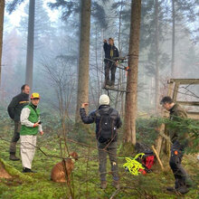 Studierende im Wald an einem Hochsitz