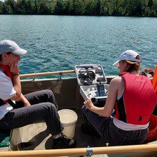 Studierende sitzen im Boot und nehmen Wasserproben