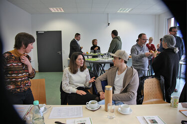 Teilnehmende der Veranstaltung sitzen an einem Tisch und unterhalten sich.