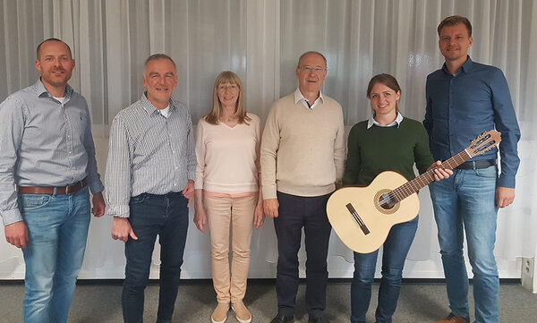 Gruppenfoto. Eine frau hält eine Gitarre in der Hand