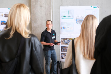 Herr vom Ingenieurbüro präsentiert etwas vor einer Stellwand vor Studierenden