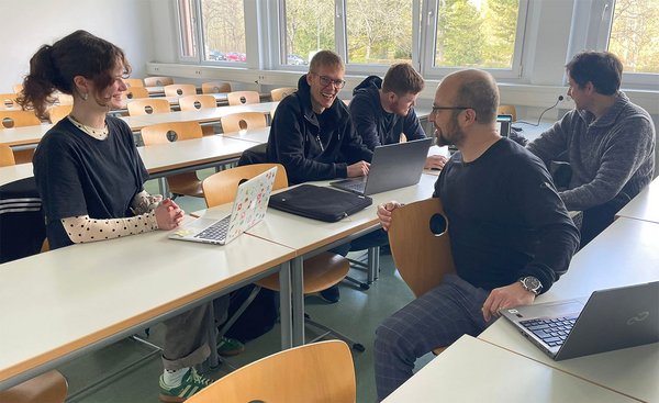 Das Team sitzt an einem Tisch und arbeitet