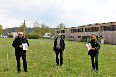 Rektor Prof. Bastian Kaiser, Kanzler Gerhard Weik und Prof. Jochen Wüst stehen mit den Verträgen in der Hand auf dem Hochschulgelände