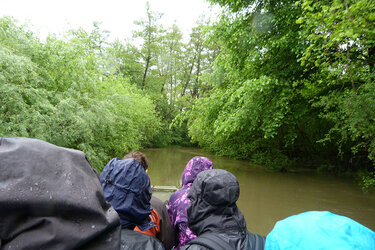 Studierende sitzen in einem Kahn auf dem Fluss