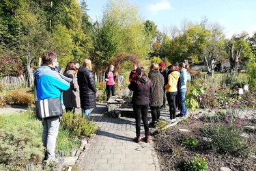 Studierende stehen im Bauerngarten des Listhofs und hören der Referentin zu