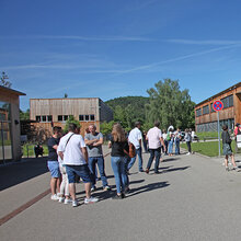 Gruppen von Studieninteressierten stehen vor den Gebäuden der Hochschule