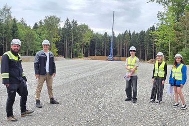 Studierende stehen auf der Baustelle und hören dem Referenten zu