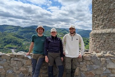 Drei Studierende vor einer Mauer