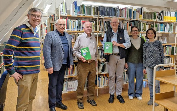 Gruppenfoto in der Bibliothek. Auf dem Foto sind der Rektor, Professoren und Angestellt der Bibliothek gemeinsam mit dem Spender Herr Weik zu sehen.