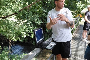 Referent steht auf einer Brücke mit einem Notebook