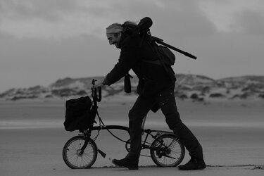 Person schiebt Fahrrad durch die Düne