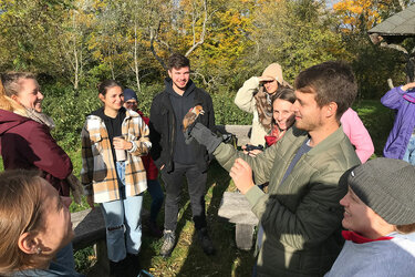 Studierende stehen um einen Studenten mit einem Vogel in der Hand