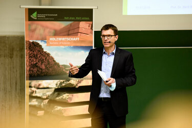 Prof. Dr. Bertil Burian moderiert auf der Bühne in der Aula der Hochschule Rottenburg