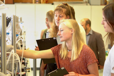Studentinnen mit Schreibbrettern stehen vor einem Versuch im Labor der Hochschule Rottenburg.