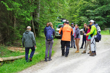 Die Teilnehmer stehen in einer Gruppe auf einem Waldweg