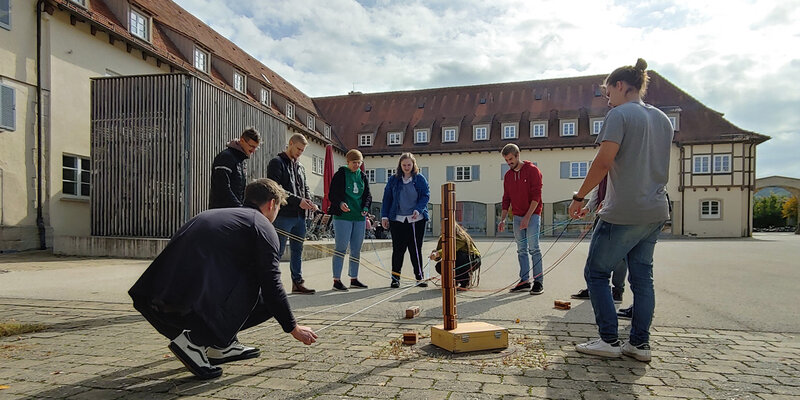 Studierende spielen im Innenhof der Hochschule zusammen ein Teamspiel 