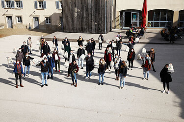 Studierende stehen im mit Abstand und Corona-Masken im Hof der Hochschule. Sie strecken den Erstsemesterbeutel in die Höhe. 