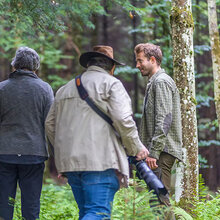 Ein Fotograf steht mit zwei anderen Personen im Wald