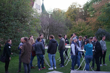 Die Gäste stehen in kleinen Gruppen an Stehtischen im Arboretum der Hochschule Rottenburg