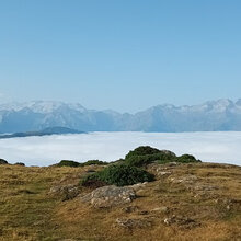 Blick über ein wolkenbehangenes Tal auf eine gegenüberliegende Bergkette
