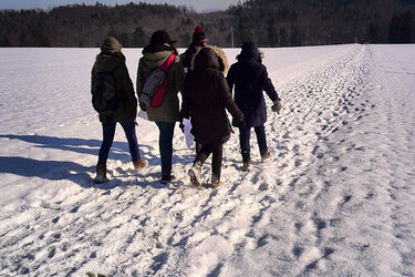 Studierende laufen über eine schneebedeckte Wiese
