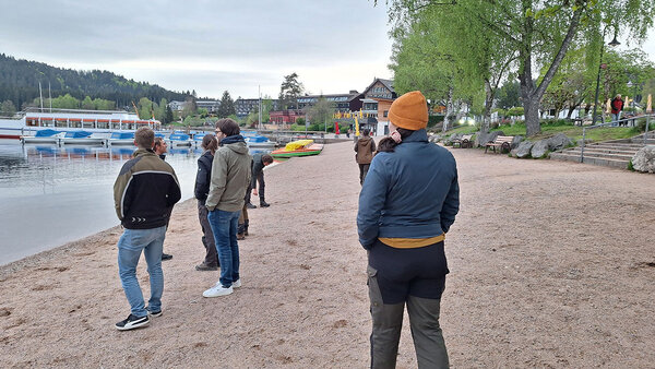 Studierende stehen am Ufer eines Sees